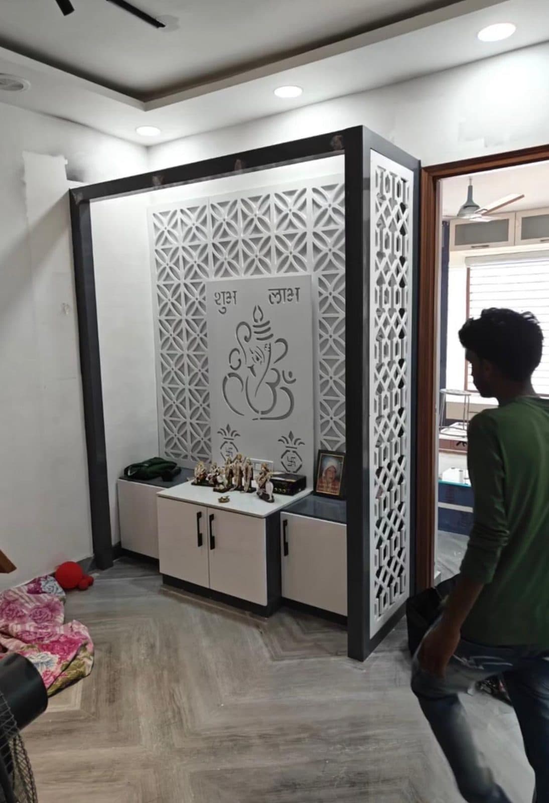 Pooja unit with white CNC-cut jali panels, Ganesh motif backdrop and storage cabinets